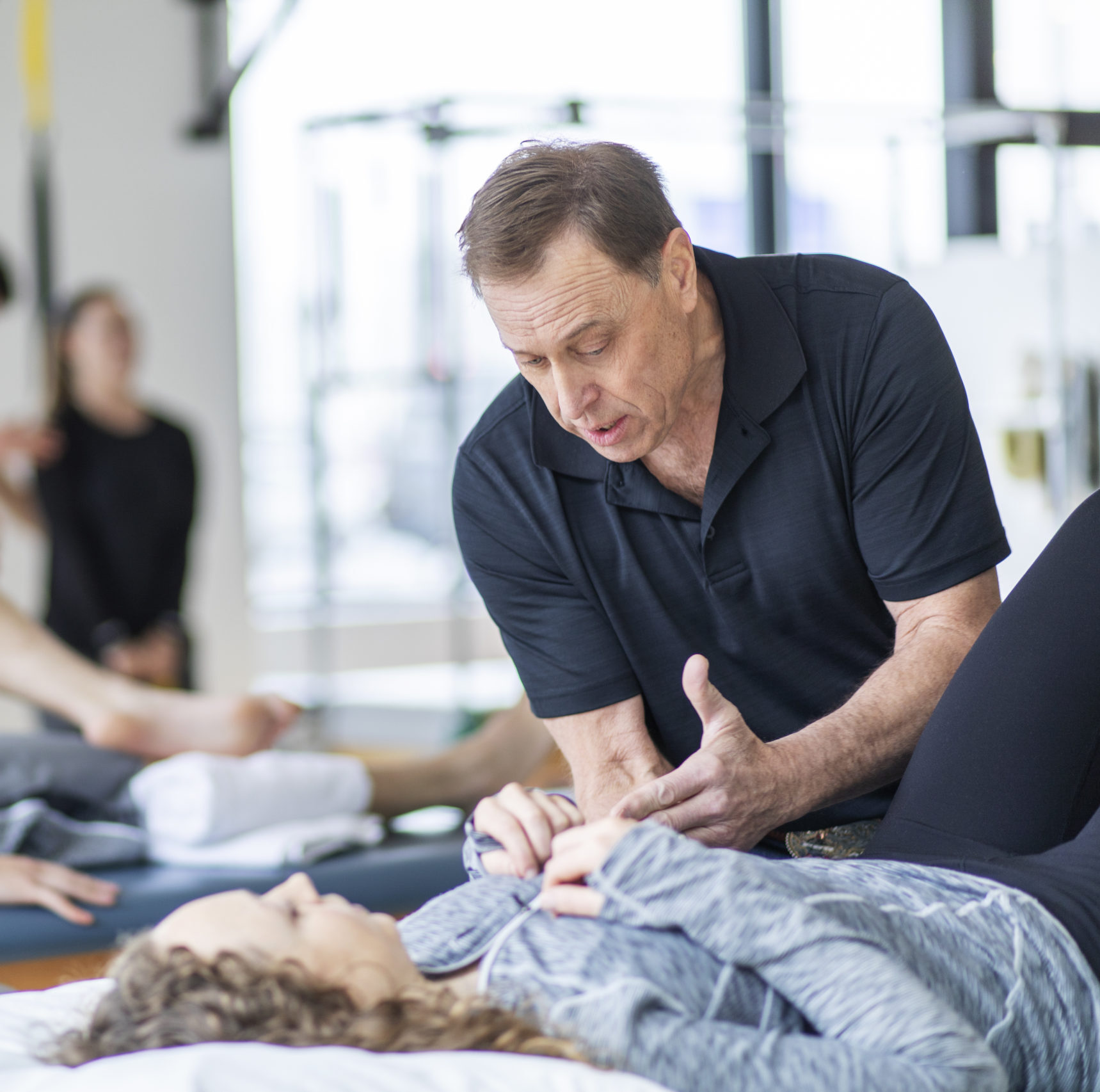 Several physical therapist working with patients on the tables.